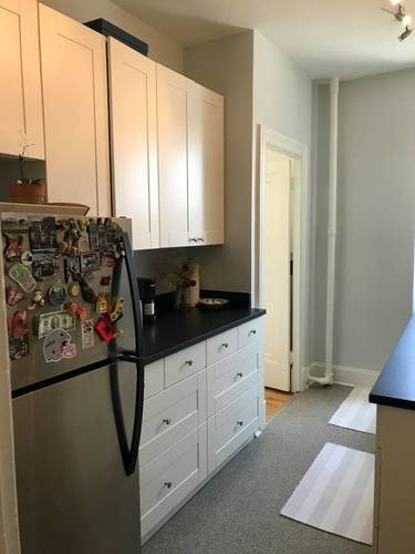 A kitchen with a refrigerator covered in magnets and white cabinets.