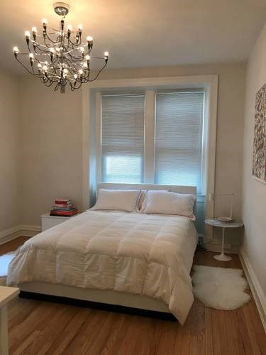 A bedroom with a large bed and a chandelier.