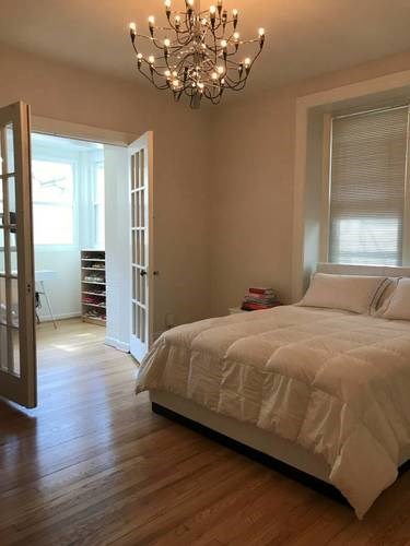 A bedroom with a large bed and a chandelier.