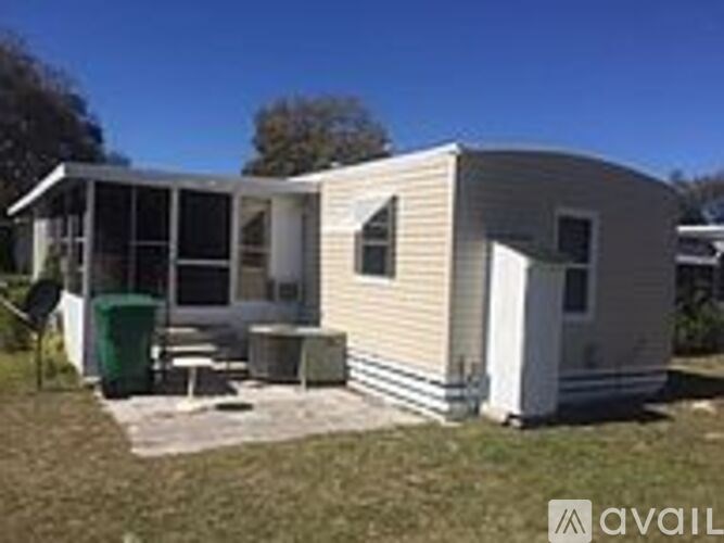 A mobile home with a white exterior and a green trash can in front.