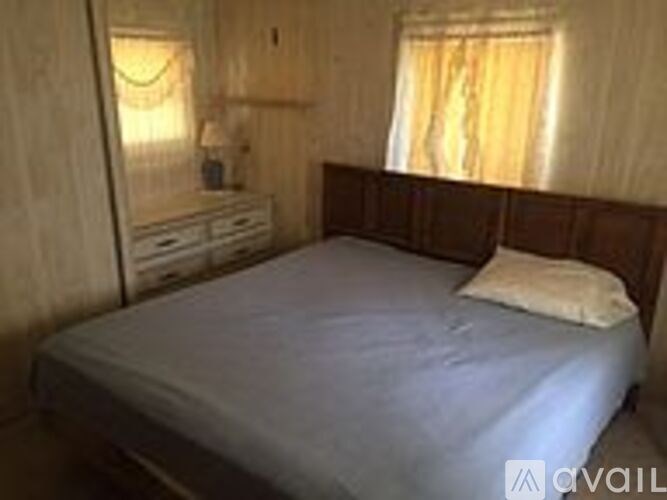 A bed with a white pillow and a grey sheet is in the image.