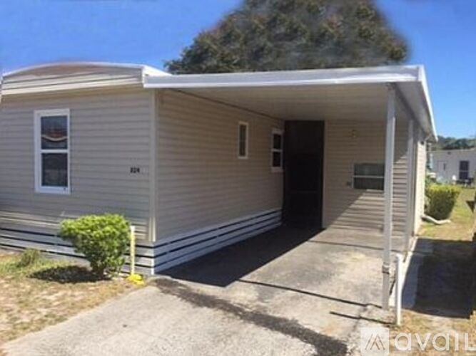 A small house with a porch and a bush in front.