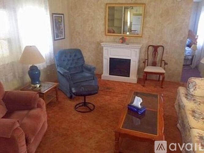 A living room with a blue chair, a fireplace, and a painting on the wall.