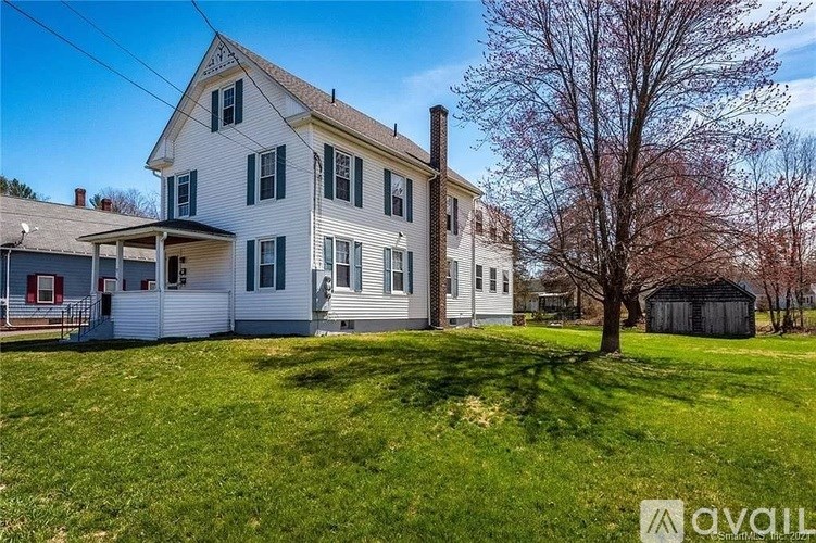 A two-story house with a white exterior and a large front yard.