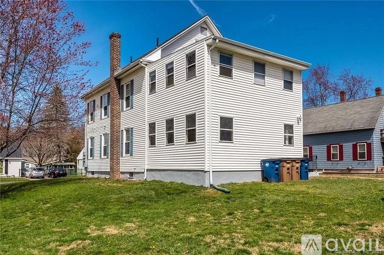 A two-story house with a white exterior and a red door.