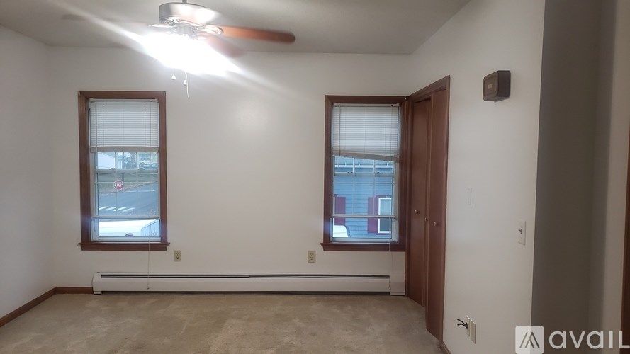 A room with two windows and a ceiling fan.