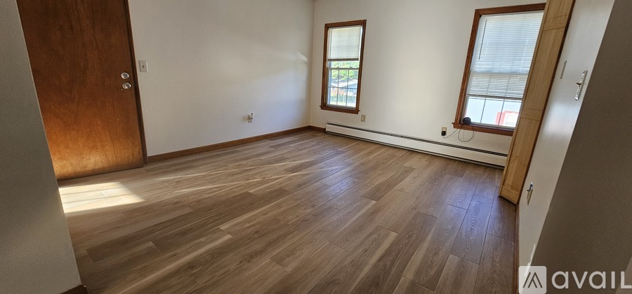 A spacious attic room with wooden floors and exposed beams.