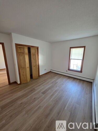 A room with wooden floors and a window with a white frame.