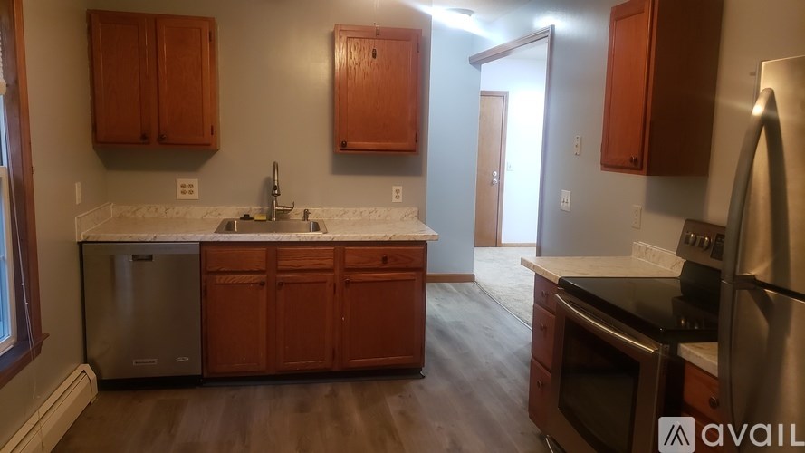A kitchen with wooden cabinets and a stainless steel refrigerator.