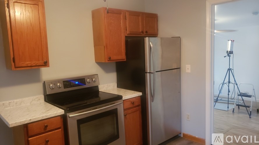 A kitchen with wooden cabinets and a stainless steel refrigerator.