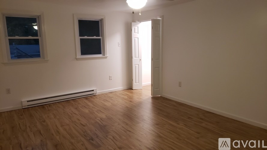 A room with wooden flooring and a window with a view of a balcony.