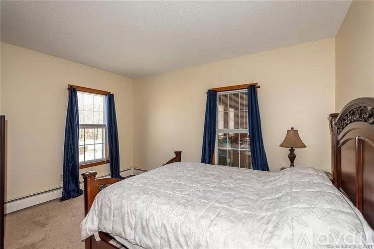 A bedroom with a large bed and a window with blue curtains.