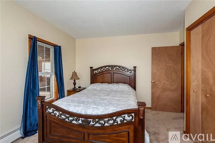 A bedroom with a wooden bed and a window with blue curtains.