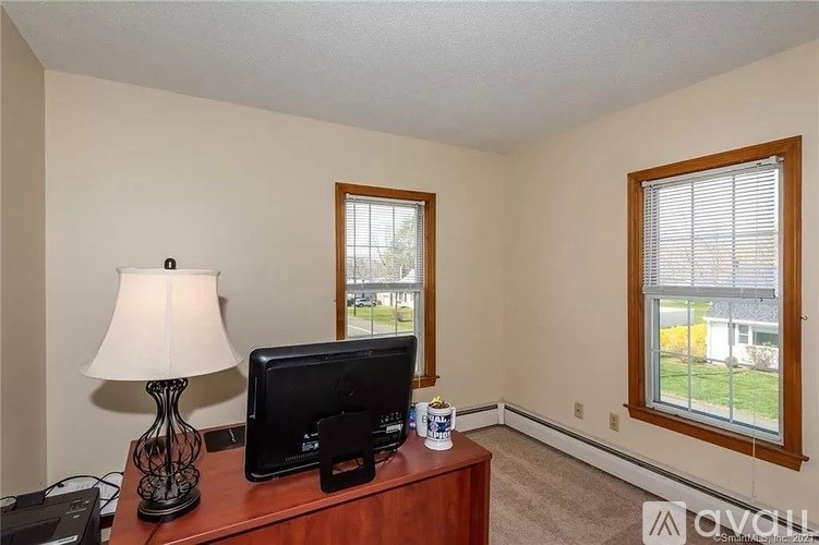 A room with a lamp, monitor, and a cup on a desk.