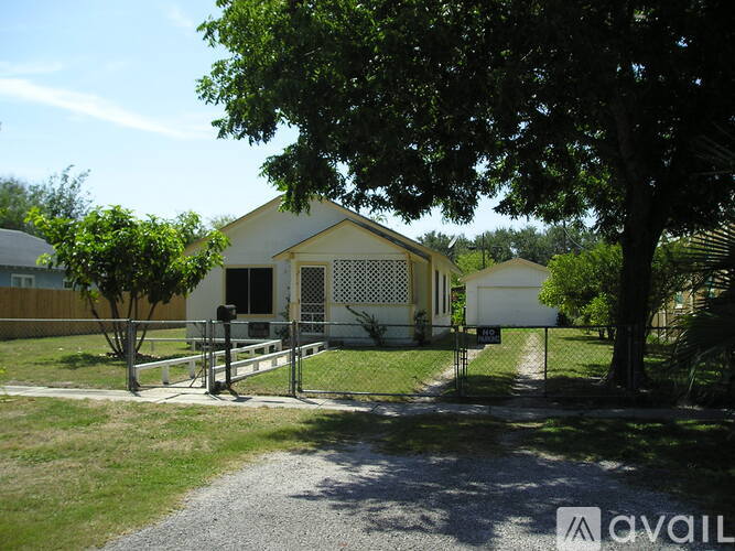 A white house with a gravel driveway in front.