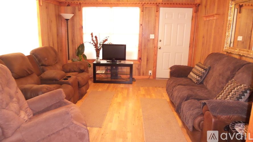 A living room with a couch, a chair, a table, and a television.