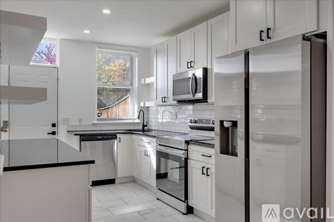 A modern kitchen with white cabinets and stainless steel appliances.