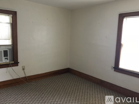 A room with a window and a fan on the window sill.