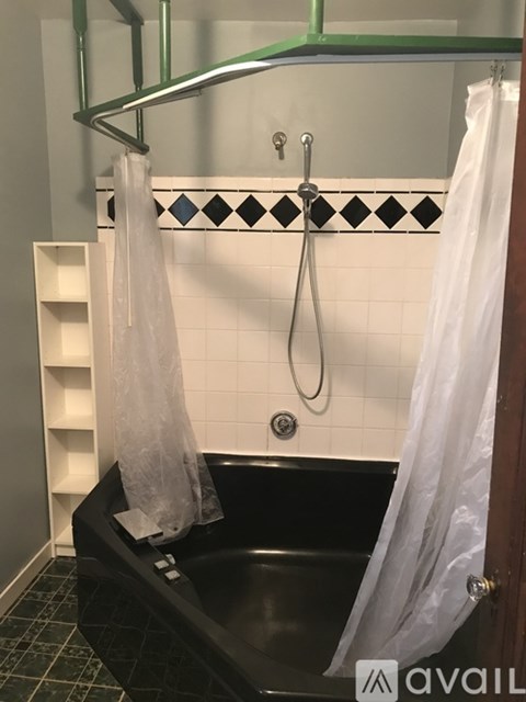 A black bathtub with a shower curtain hanging from a rod.