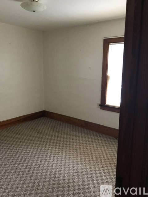 A room with a carpeted floor and a window with a curtain.