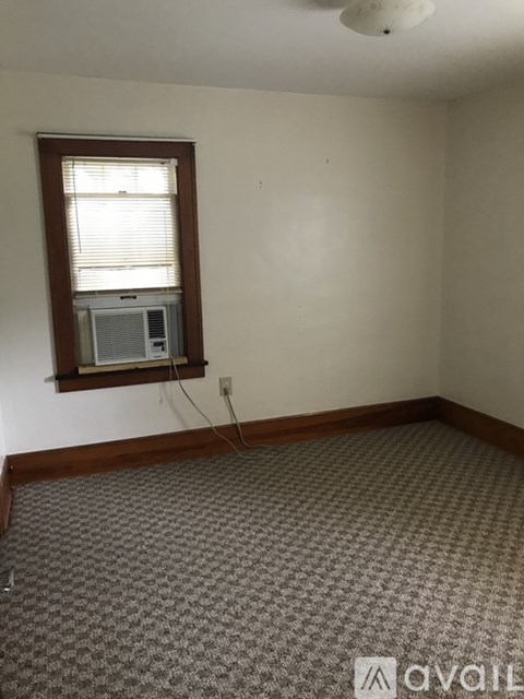 A room with a window and a carpeted floor.