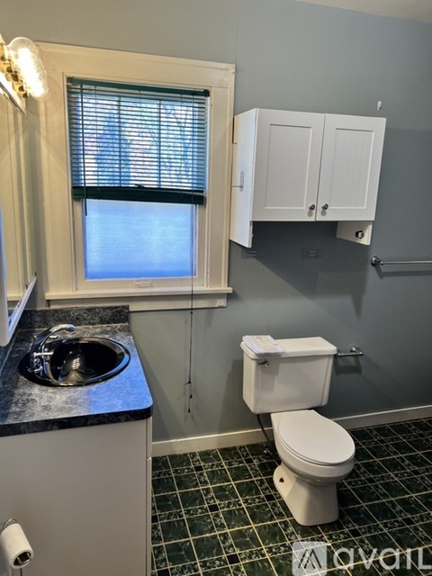 A white toilet sits in a bathroom with a pink wall.