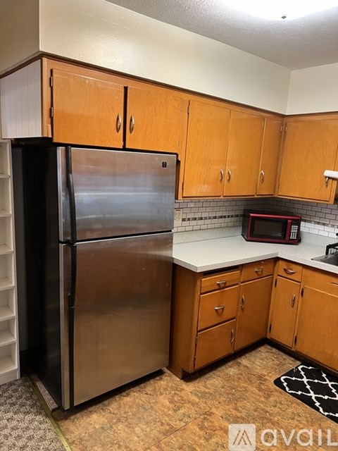A kitchen with a stainless steel refrigerator and wooden cabinets.