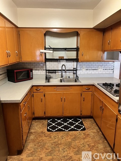A kitchen with wooden cabinets and a black and white rug on the floor.
