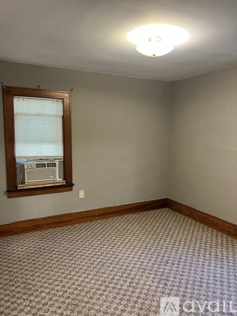 A room with a window and a carpeted floor.