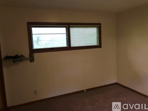 A room with a window and a wall-mounted shelf.