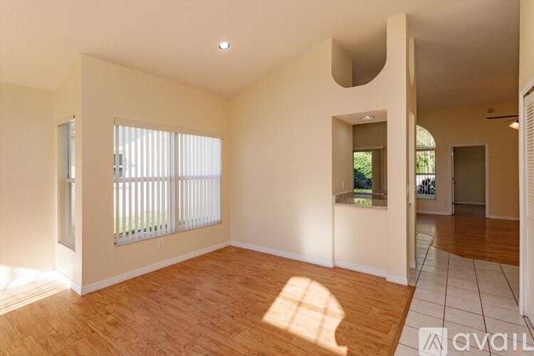 A sunny room with wooden floors and a window with blinds.