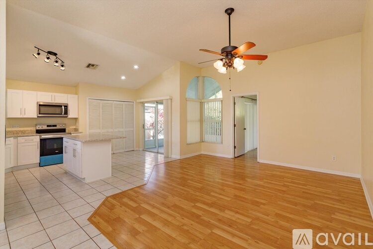 A spacious kitchen with a fan and wooden flooring.