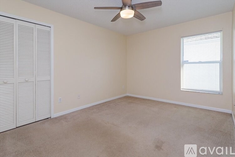 A room with a ceiling fan and a window with blinds.