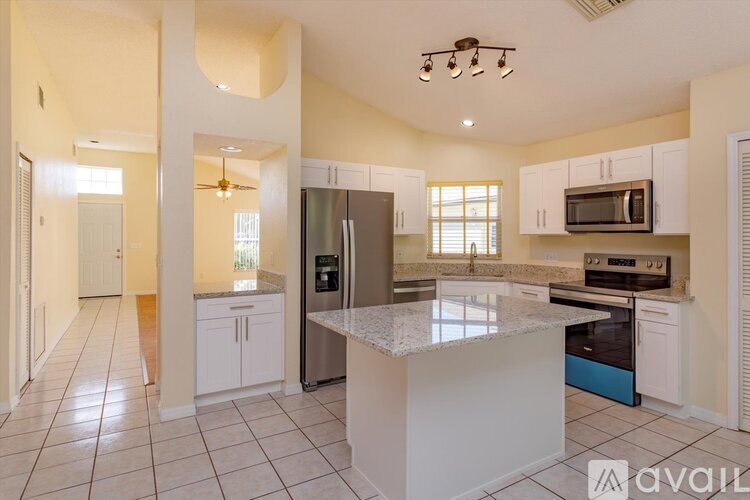 A kitchen with a white island and stainless steel appliances.