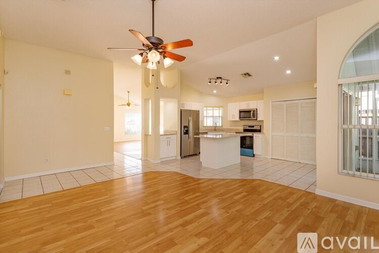 A spacious living room with a ceiling fan and hardwood floors.