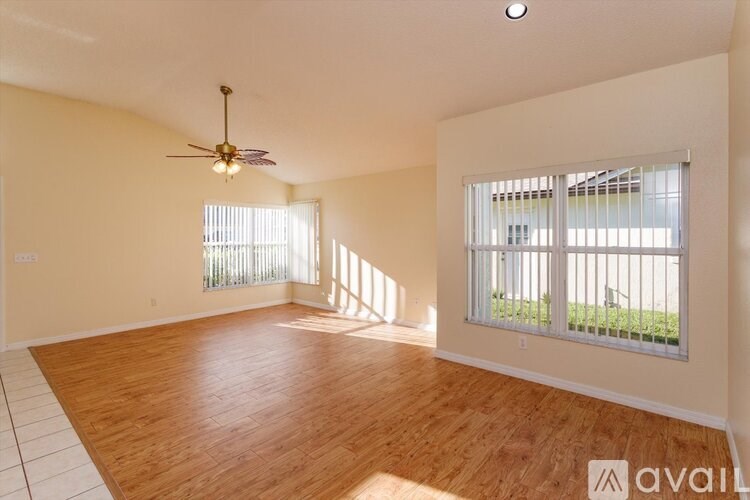 A spacious room with wooden flooring and a ceiling fan.