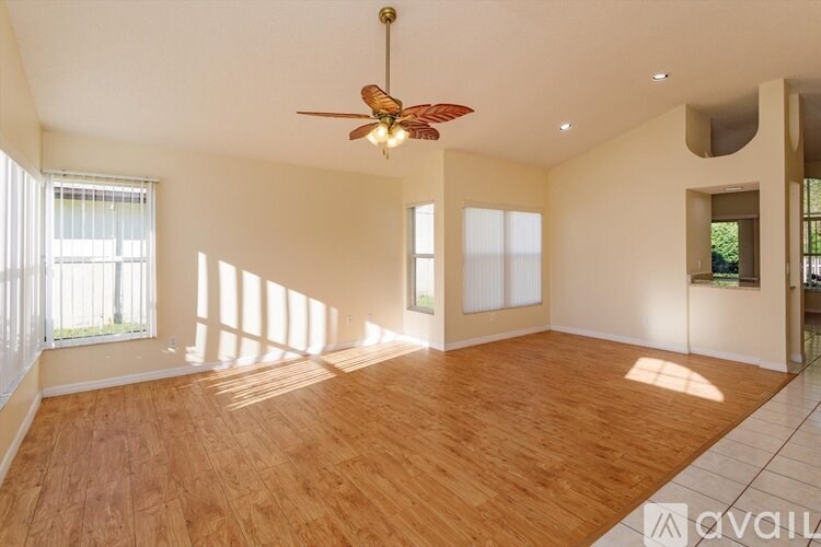 A spacious room with wooden flooring and a ceiling fan.