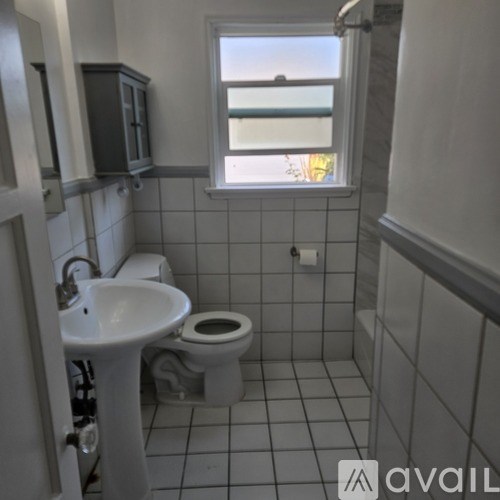 A bathroom with a toilet, sink, and a window.