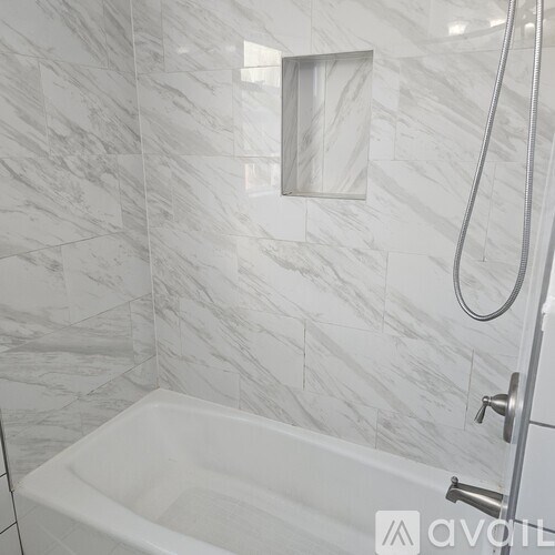 A white bathtub in a bathroom with marble tiles.