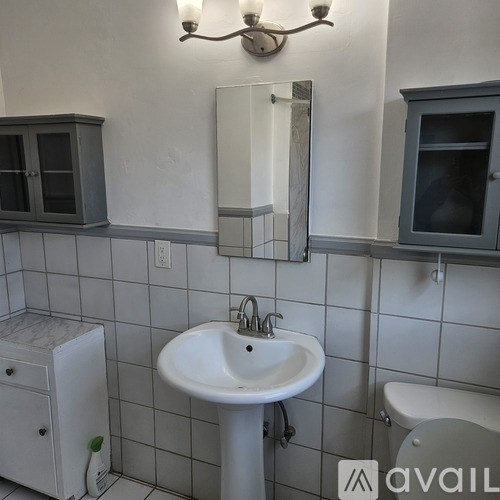 A bathroom with a white sink and grey cabinets.