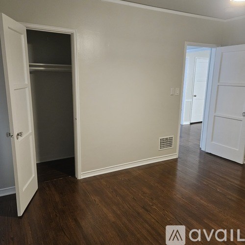 A room with a white door and a wooden floor.