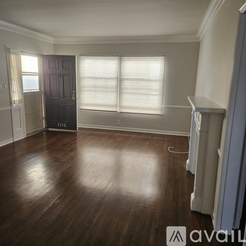 A room with a dark wooden floor and a black door.
