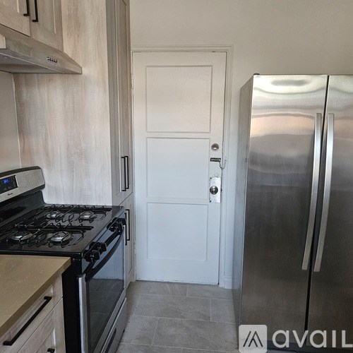 A kitchen with a stove, refrigerator, and a door.