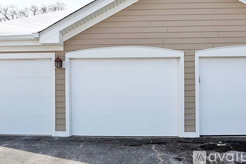 Two white garage doors on a tan house.