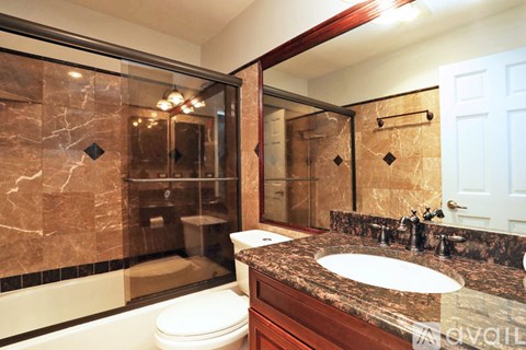 A bathroom with a marble counter top and a walk in shower.
