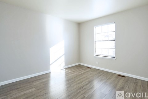 A room with wooden flooring and a window with blinds.