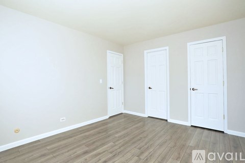 Three white doors are in a room with wood floors and white walls.