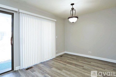 A room with wooden flooring and a hanging light fixture.