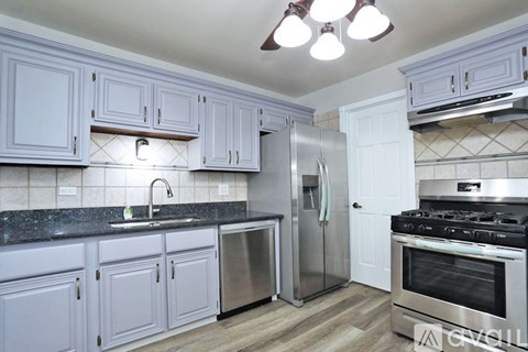 A kitchen with white cabinets and a black countertop.