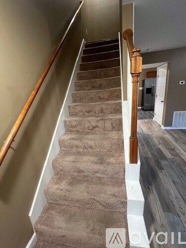 A staircase with a wooden handrail and beige carpeted steps.